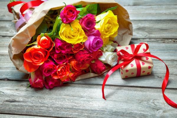 A bouquet of roses of all different colors and a small gift