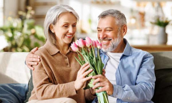 A man exchanges holiday flowers with a woman