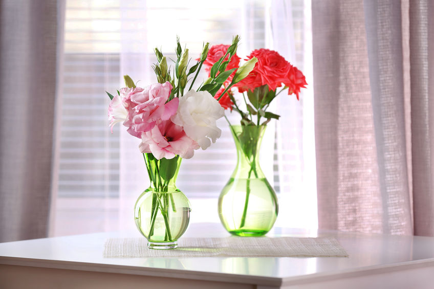 pair of flowers in vases sitting on table in front of window