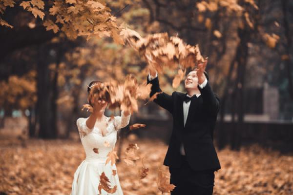 A couple celebrates their wedding by throwing leaves in the air.